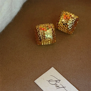 Detailed view of hollow cube earrings with gold plating and intricate geometric mesh texture