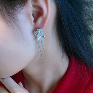 Gros plan de boucles d'oreilles rose élégantes avec zircons, perles et glands rubans