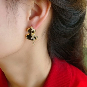 Detail of elegant gourd earrings with a black glaze and diamond bow on a female model
