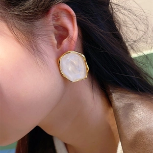 Macro view of vintage oval resin earrings with gold plating on model's ear