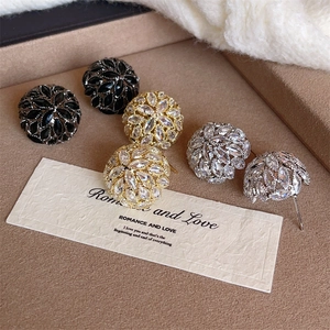 Detailed close-up of crystal hydrangea earrings in gold, silver, and black on a velvet tray