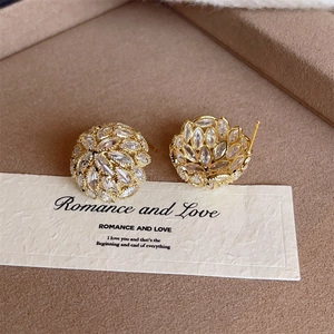 Macro detail of gold floral stud earrings with marquise-cut crystals on brown velvet