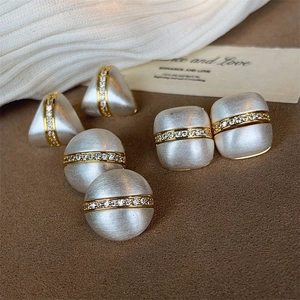 Three pairs of geometric brushed silver earrings with gold band and pave crystal accents