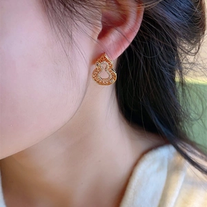 Élégantes boucles d'oreilles gourde évidée en or avec zircons, portées par un mannequin