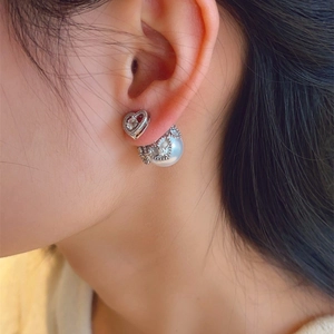 Detail of silver heart earrings with pearls and zircon stones shown on a model's ear