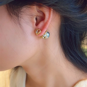 Detailed view of heart-shaped pearl earrings with zirconia on female model