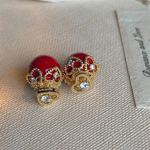 Macro shot of red heart pearl earrings with gold hollow lace and zircon inlay details