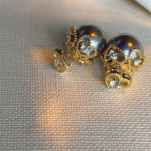 Macro detail of heart-shaped zircon earrings with grey pearls and crown patterns