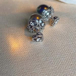 Macro detail of heart-shaped silver earrings with grey pearls and sparkling zircon stones
