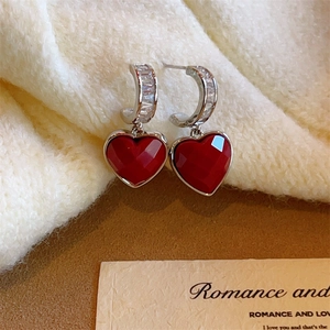 New Year red heart earrings with zircon inlay and silver hooks on cozy winter background
