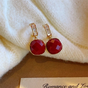 Detail of red square zircon earrings with gold plating on a cozy knit background