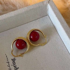 Detail of vintage gold twisted hoop earrings with large festive red faux pearls