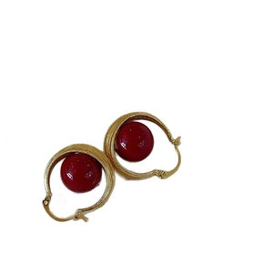 Elegant gold hoop earrings featuring large festive red pearl beads in a vintage style