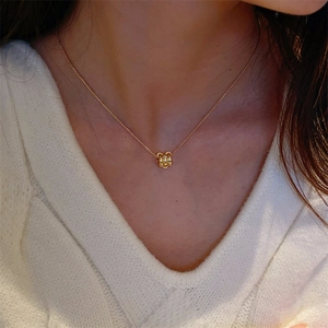 Elegant gold necklace with sparkling zircon cylinder pendant worn with white knit sweater