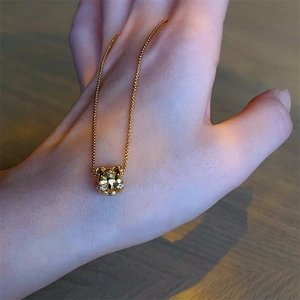 Luxury gold cylinder pendant necklace with sparkling zircons on a delicate metal chain