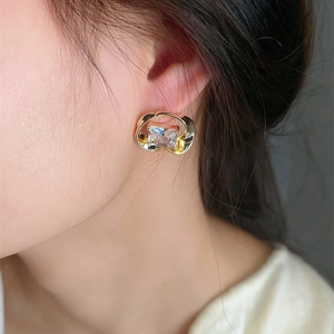 Elegant gold square glass crystal earrings with ribbon wrap design on model ear