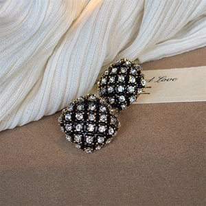 Close-up of vintage gold-plated hemisphere stud earrings with black base and clear rhinestones
