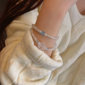 Close-up of double-layered moonstone bead bracelets featuring a hollow flower carving charm