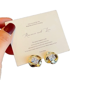 Elegant gold twisted frame stud earrings with square clear zircon on a display card