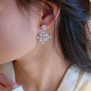 Elegant silver snowflake earrings with sparkling zircons worn by a female model