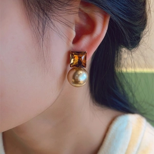 Elegant gold pearl earrings with square amber crystal studs shown on a model
