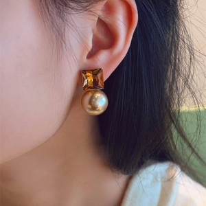 Elegant gold pearl earrings with square champagne crystal on female model