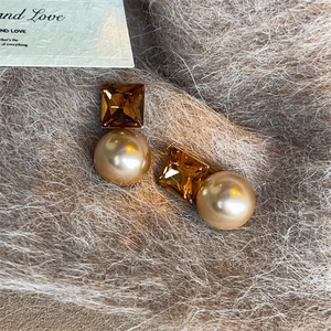 Elegant gold pearl earrings with square amber crystals on a plush background