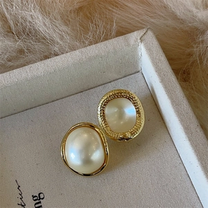 Detailed close-up of vintage style pearl stud earrings with smooth and hammered gold edges