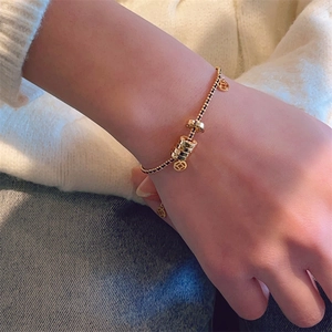 Exquisite gold and black beaded bracelet with traditional coin charms on a model's wrist