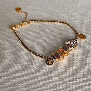 Close-up of gold copper coin bracelet with pave zircon beads and adjustable chain detail