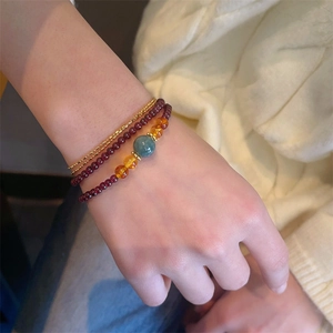 Three-layer garnet bracelet with jade bead and amber accents on female wrist