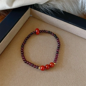 Macro detail of garnet double-loop bracelet with red beads and gold spacers on velvet