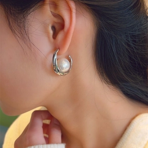 Elegant C-shaped silver hoop earrings with large pearl on model for a minimalist look