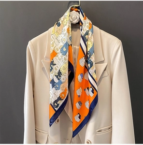 Dettaglio di un foulard di seta con gatti su un blazer beige con clip a fiore bianco