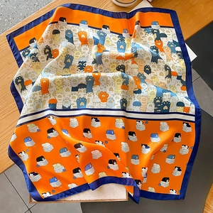 Dettaglio ravvicinato di un foulard in seta arancione con stampe di gatti