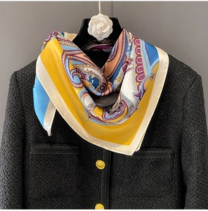 Close-up of silk-feel square scarf with paisley pattern styled on a tweed jacket