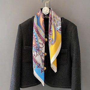Colorful paisley silk scarf styled on a black tweed jacket over a gray background