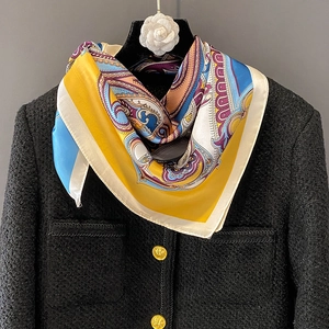 Elegant silk-like square scarf with paisley print styled on a black tweed jacket