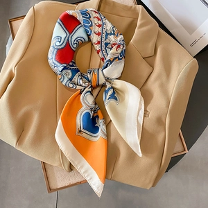 Elegant printed silk scarf with paisley and heart patterns on a khaki suit blazer