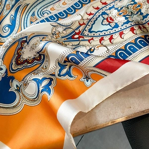 Close-up of silk-like scarf with detailed paisley patterns on marble background