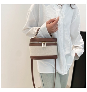 Detail of linen and brown leather bucket bag with gold zippers worn by a model