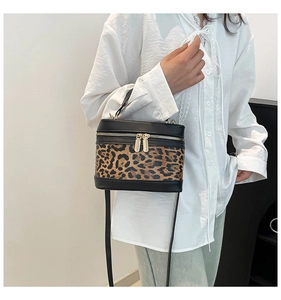 Detail of leopard print crossbody bag with gold zippers and black leather trim