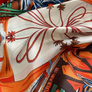 Close-up of printed silk scarf with floral patterns and orange satin texture details