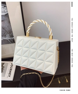 Detailed macro view of white geometric quilted box bag with unique gold braided handle
