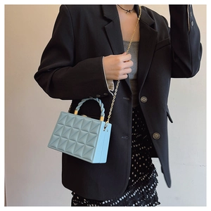 Detail of light blue box bag featuring 3D geometric quilted texture and gold chain strap