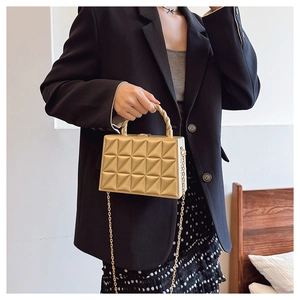 Detail of golden 3D geometric quilted evening bag with a designer twisted metal handle