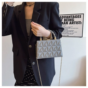 Detail of grey crossbody bag with geometric quilted pattern and gold chain strap