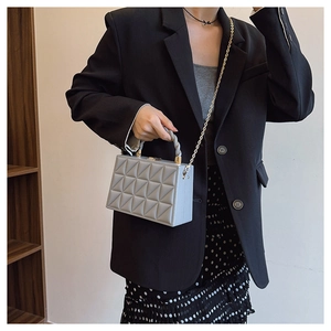 Close-up of geometric quilted texture on stylish shoulder bag with woven handle