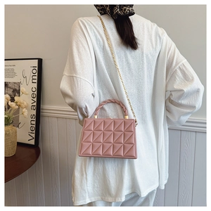 Detail of pink quilted handbag with geometric texture and elegant gold chain strap