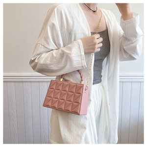 Detailed macro view of pink quilted box bag with golden chain and knot handle